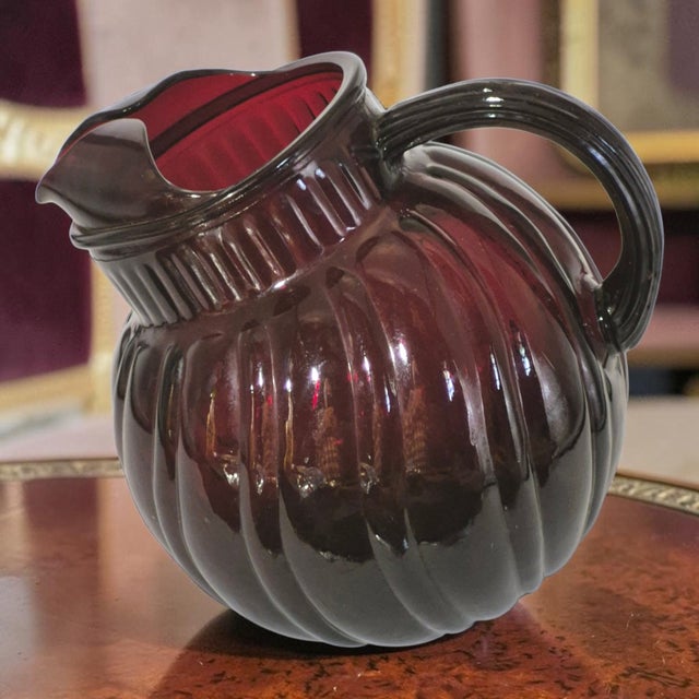 The Vintage Anchor Hocking Royal Ruby Red Swirl Tilted Ball Pitcher is a mid-century modern piece of glassware from the...