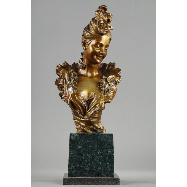 Bust of a young woman from the Belle Epoque period, in bronze with a golden patina, resting on a green Alpine marble...