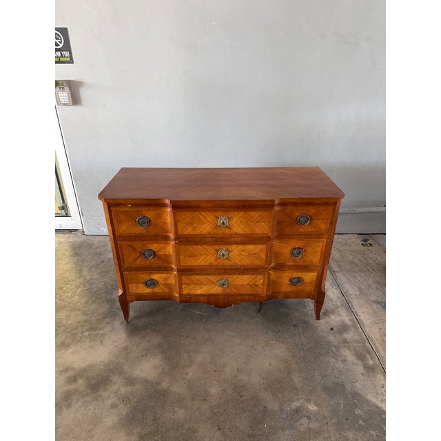 A French Louis XVI serpentine-front commode, featuring herringbone veneered walnut, original ornate bronze escutcheons,...