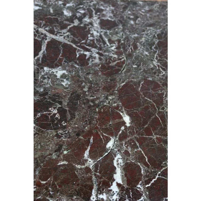 Game table in carved walnut, built-in marble, late XIX era. The four feet in the shape of claws are united by a spacer...