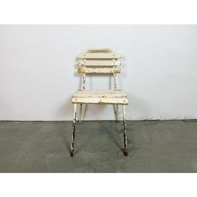 This beige chair was made in former Czechoslovakia during the 1960. It features an iron construction and a wooden seat and...