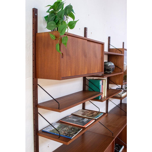This wall shelf by Poul Cadovius combines ample storage space with an open and pleasantly light design. The warm wood...