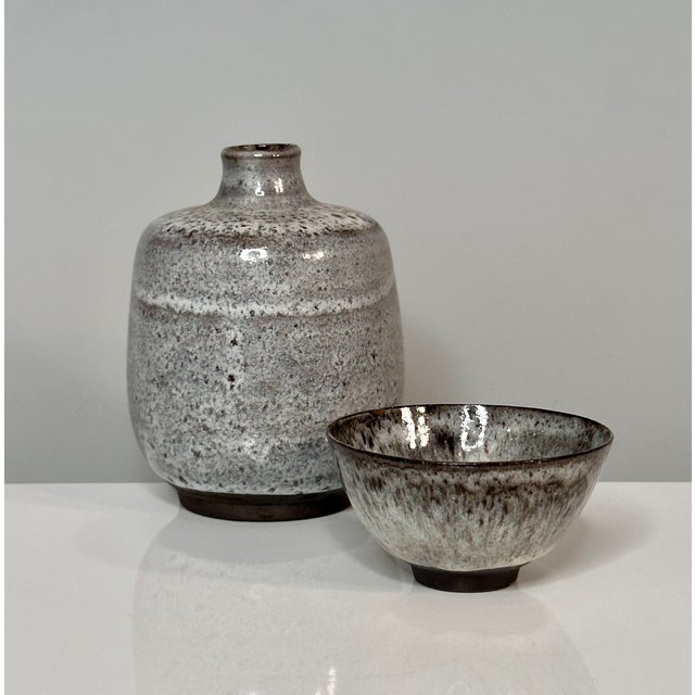 An impressive set of two studio ceramic art vessels including a bottle-shaped vase and a small bowl, created by the renown...