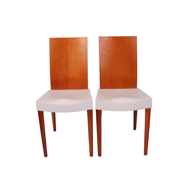 A pair of dining side chairs by Philippe Starck for Kartell. Light gray molded polypropylene seat, beechwood legs and...