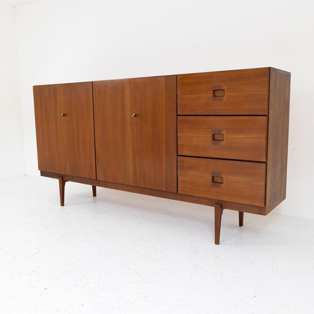 Elegant Italian sideboard from the 1960s in teak wood with light maple interior. The cabinet has three large drawers on...