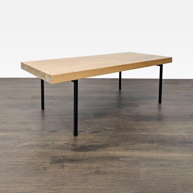 This EQ3 coffee table features a sturdy wood top and sleek black metal legs, offering a modern and minimalist look....