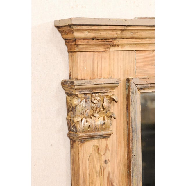 A tall French mirror with architectural accents from the late 19th century. This antique mirror from France has a...