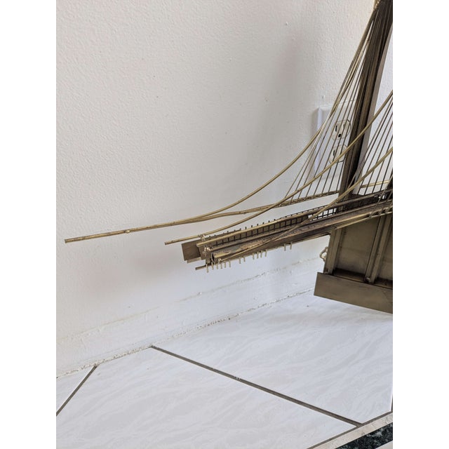 A 1976 wall-mounted metal sculpture of the Brooklyn Bridge by Curtis Jere with a certificate of authenticity.