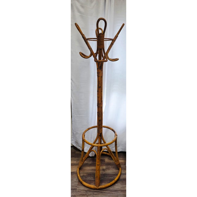 This is a vintage mid-century bamboo and rattan standing coat rack featuring a distinctive circular umbrella holder near...