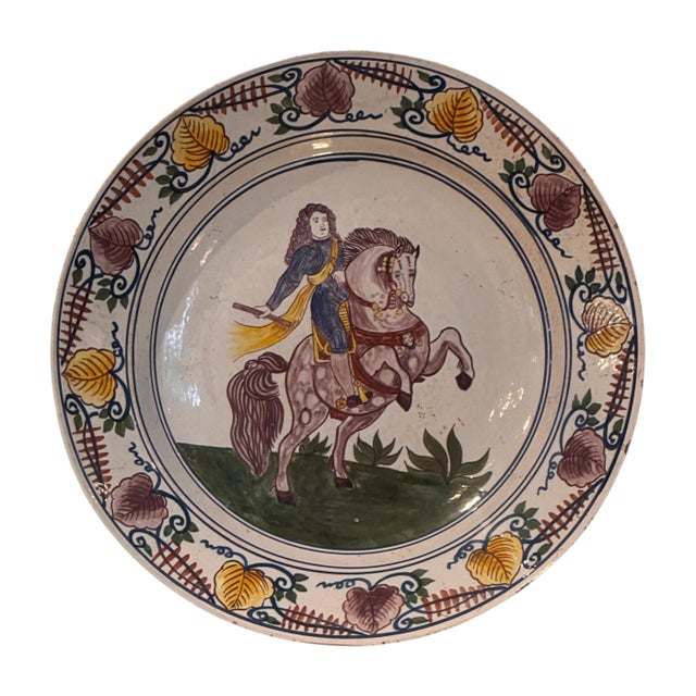 A pair of 18th century Delft chargers with polychrome decoration. Each plate centers a mounted figure within a double blue...