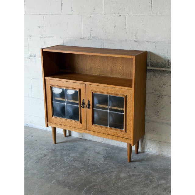 This versatile display cabinet features open upper shelving and an enclosed lower storage compartment with leaded glass...