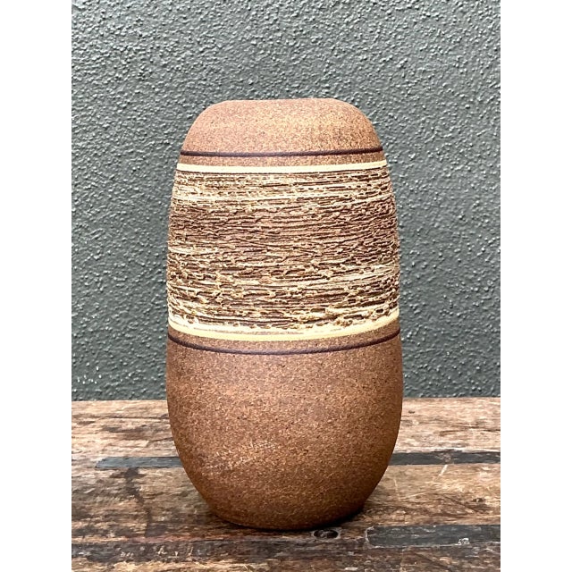 Dating to the Mid-Century Modern era, this vintage studio pottery vase is crafted from ceramic with a gently rounded body...