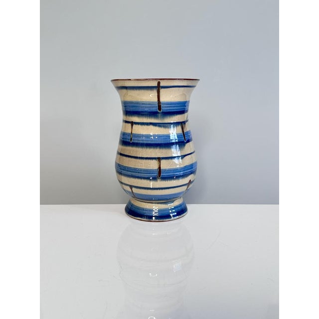 This handcrafted ceramic vase from the 1920s combines clean lines with a striped decoration in cream and azure,...