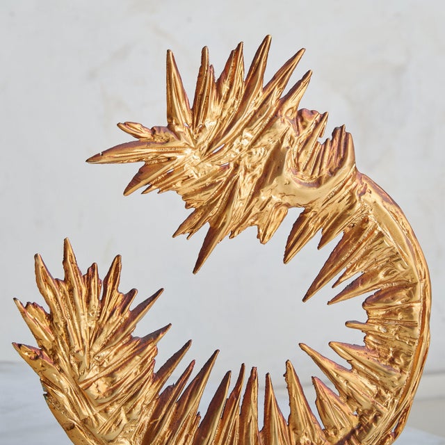 An abstract sculpture by French artist Philippe Cheverny, rendered in gilded metal. Its Brutalist form emerges from molten...