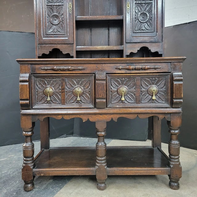 This handsome carved oak 2 drawer dresser with 2 cupboard rack is a great accent piece of a dining room and kitchen....
