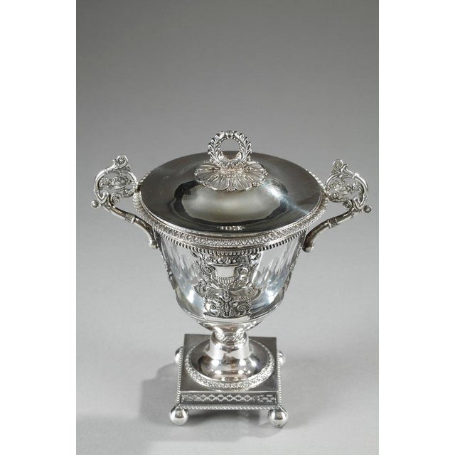 Slightly tapered candy dish in silver and crystal. The rim is ornamented with an openwork geometric frieze, and the paunch...