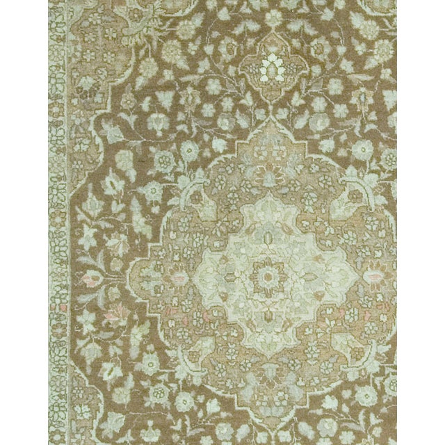 An antique Tabriz rug featuring a central medallion adorned with exquisite floral details, all elegantly enclosed within a...