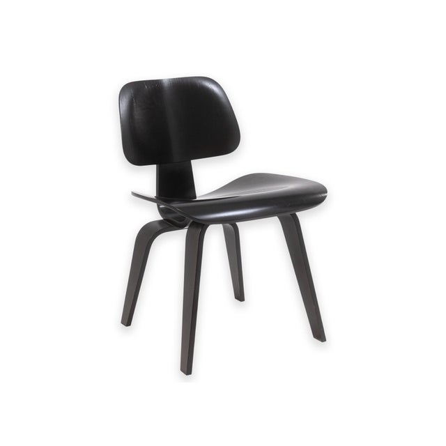 A black DCW (Dining Chair Wood) designed by Charles and Ray Eames for Herman Miller. The chair features a molded plywood...