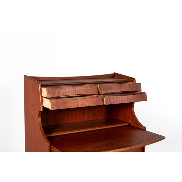 This elegant vintage secretary desk is made of warm teak wood and features a timeless mid-century modern design. It offers...