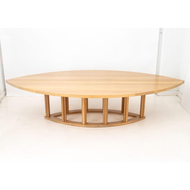 Contemporary Pointed Oval Blonde Wood Dining Table, the top above ten cylindrical supports mounted on pointed oval base....