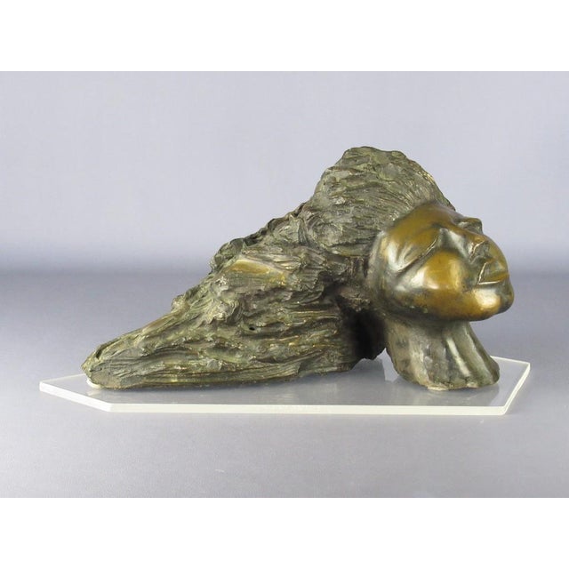 Stunning sculpture depicting an anthropomorphic head with long hair, solid and heavy bronze casting, completely worked and...