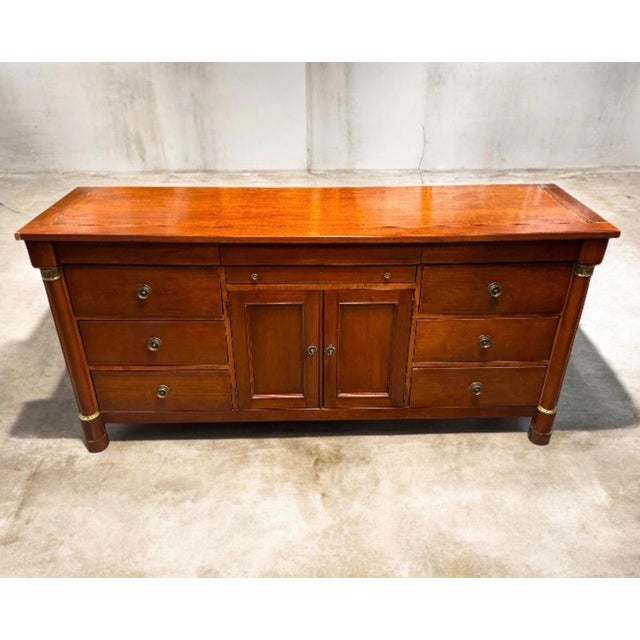 This particular sideboard, crafted from walnut, showcases the Neoclassical aesthetic with its clean lines, tapered legs,...