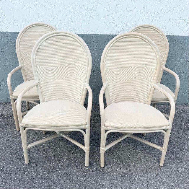 Elegant boho chic dining arm chairs crafted in pencil reed and rattan, featuring softly arched backs with a subtle wave...