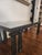 Postmodern lacquered wrought iron coffee table with ionic column table legs and inner step detail under glass top. Slight...