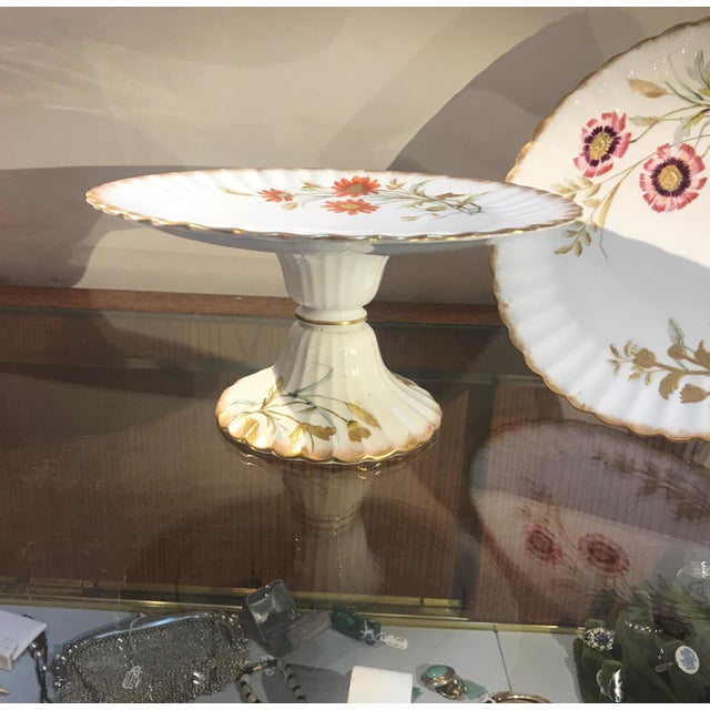 Elegant pair of hand painted and raised gilt English compotes. The scalloped tops with beautifully decorated floral and...
