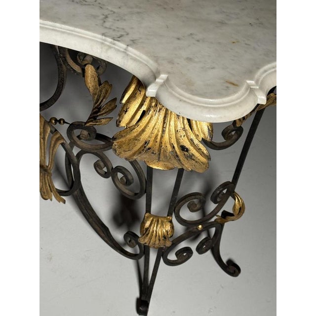 Richly decorated vintage console / side table. Crafted in wrought iron with a Carrara marble top. Gold-colored decoration...