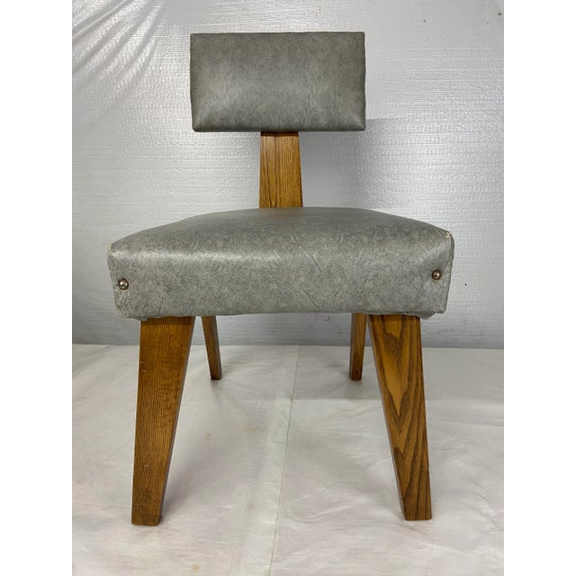 Single mid century modern boxy armless chair with exposed angled oak wood legs and vinyl upholstered back and seat....