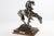 Cast in rich patinated metal (pewter/cold-cast bronze finish), the sculpture captures the exhaustion and quiet resilience...