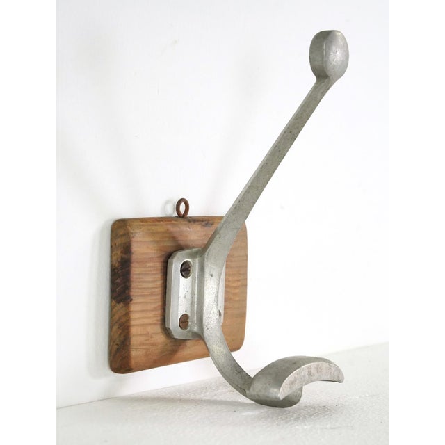 Vintage European wall hook made of an aluminum two arm hook mounted on a wood base. The original mounting screws are not...