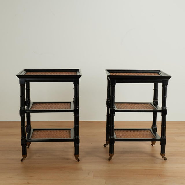 Standout pair of vintage British colonial style stands with an ebonized finish, having three caned tiers on turned faux...