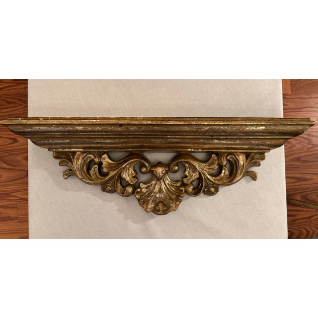A guilded gold finish encompasses the body of this Rococo Revival wall shelf and highlights its intricate carvings. A...