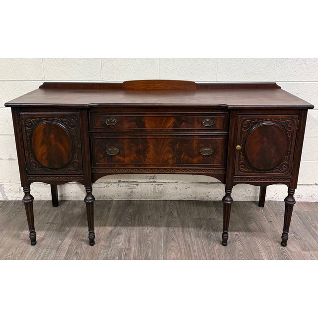 This is a gorgeous and elegant antique Edwardian Sheraton Revival or Federal sideboard crafted in richly figured flame...