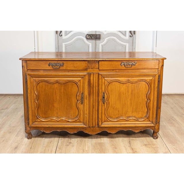 A French Louis XV period walnut buffet from circa 1770 with two drawers over carved doors and skirt. This French Louis XV...