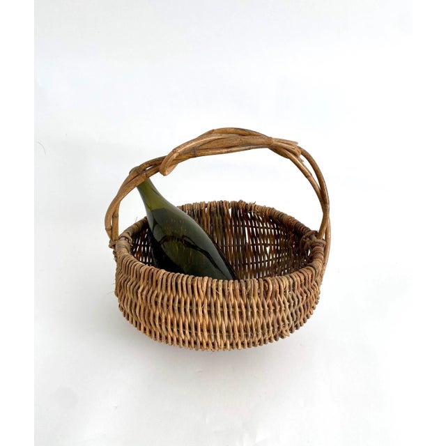 Rustic hand-made woven wicker and grapevine basket with freeform handle.