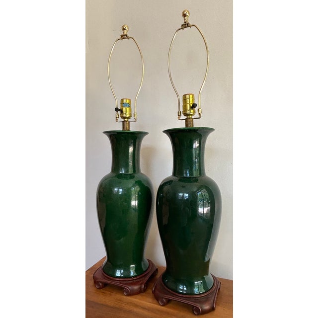Gorgeous pair of forest green porcelain urn form table lamps set on a ceramic scroll-foot base. Please see condition...
