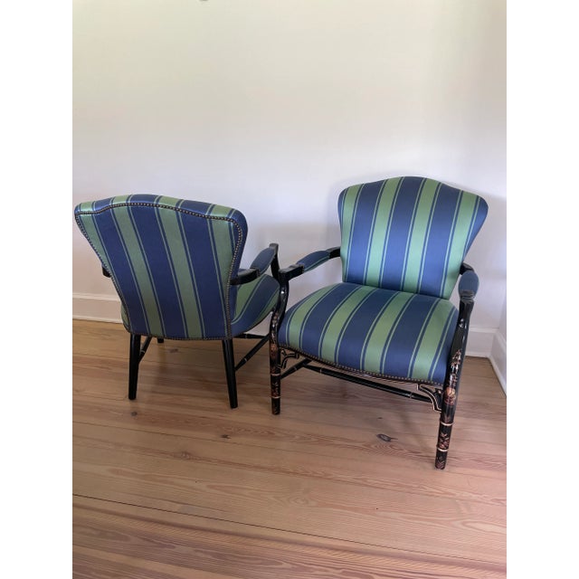 Upholstered chairs in green and blue cabana stripe fabric, finished with brass nailhead details on a black lacquered...