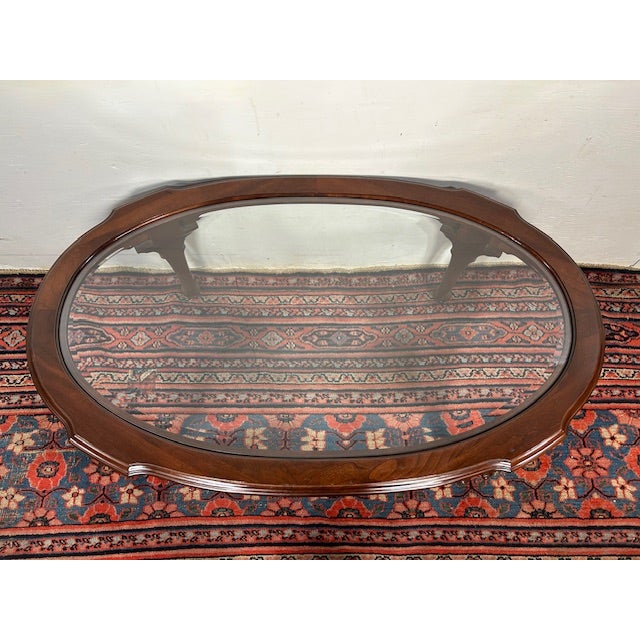 This oval glass-top coffee table brings a clean, open feel to a living room while still offering the warmth of a classic...