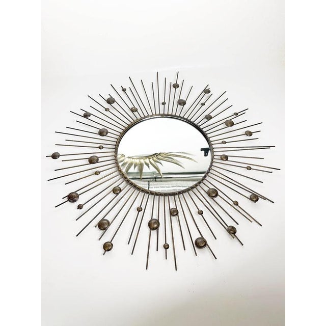 Decorative round wall mirror dating from the 1980s, featuring a striking sunburst design composed of numerous slender iron...