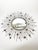 Decorative round wall mirror dating from the 1980s, featuring a striking sunburst design composed of numerous slender iron...