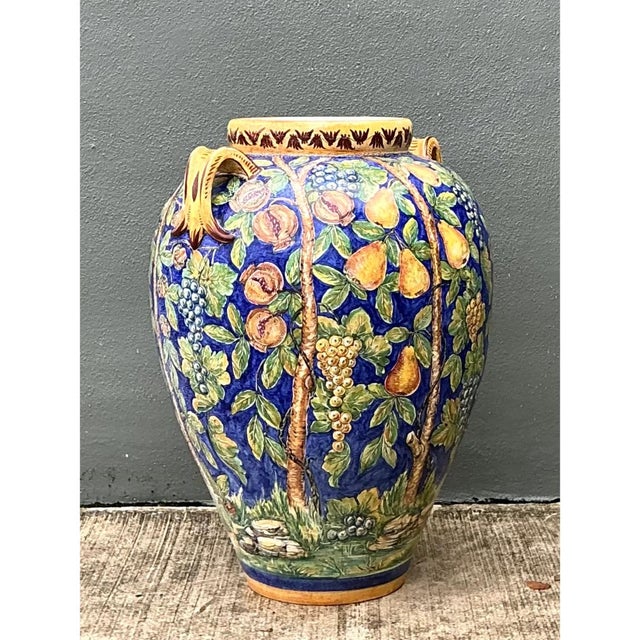 This vintage Italian terracotta urn presents a grand, bulbous silhouette, swelling generously from a narrow foot to a...