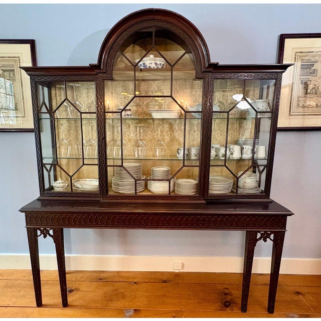 A meticulously crafted antique Chippendale style carved mahogany two-part display china cabinet with a distinctive arched...