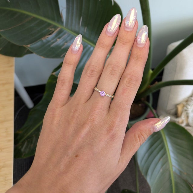 A natural purple sapphire sits at the center of this round ring, encircled by a sparkling halo of diamonds in solid 14K...