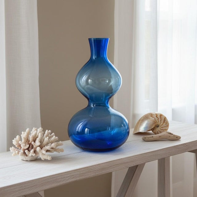Add striking color and sculptural form to any interior with this vintage hand-blown translucent blue art glass vase. Its...