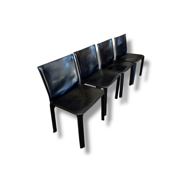 Set of four iconic Cassina leather dining chairs, made in Italy. These sleek black leather chairs feature a sculptural...