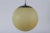 Original Art Deco pendent light with ball-shaped shade of matte light yellow glass made in the 1930s. The shade is mounted...
