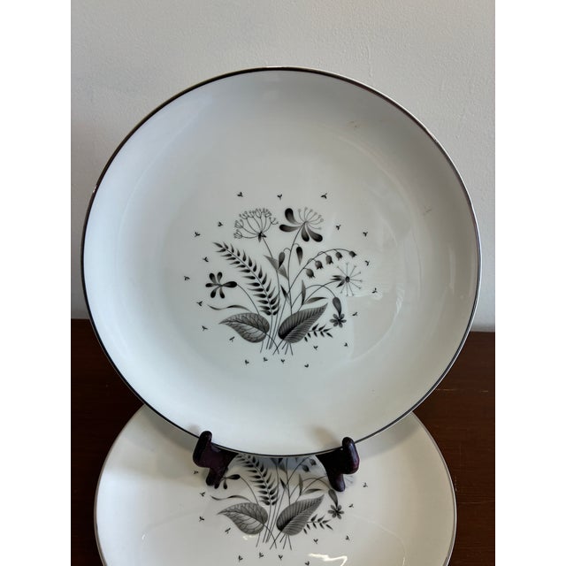 A sophisticated pair of Royal Jackson “Parisienne Deauville” plates featuring a delicate black botanical motif centered on...